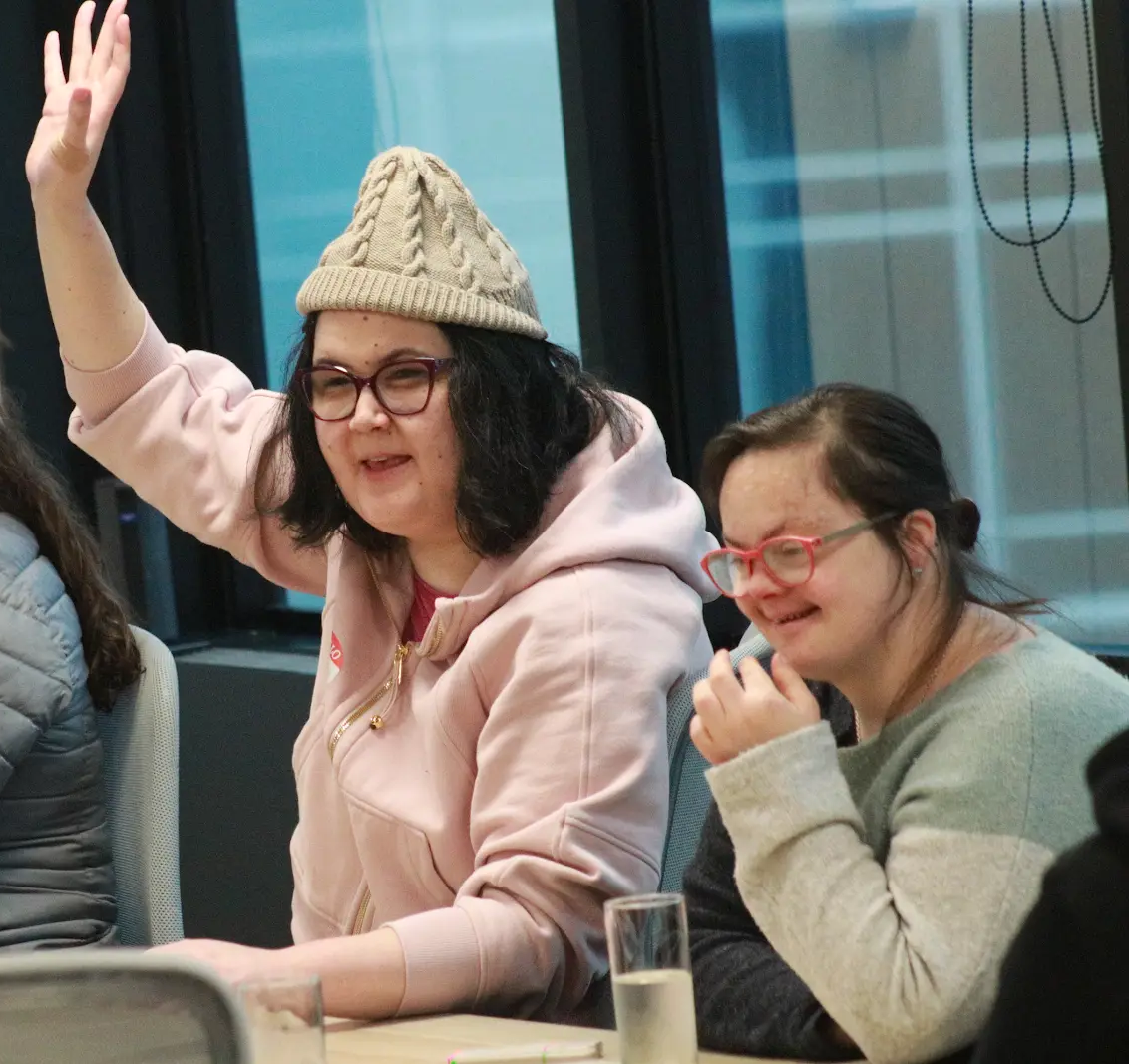 A volunteer raising her hand and smiling beside a participant during an Access Lab coaching session