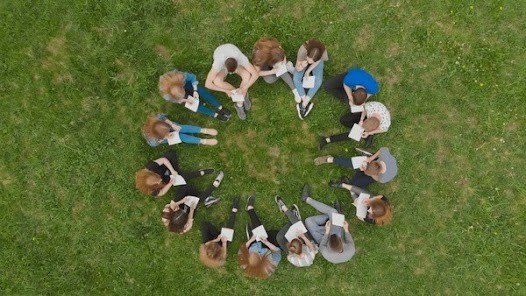 Students seen from a birds eye view sitting in a circle on grass